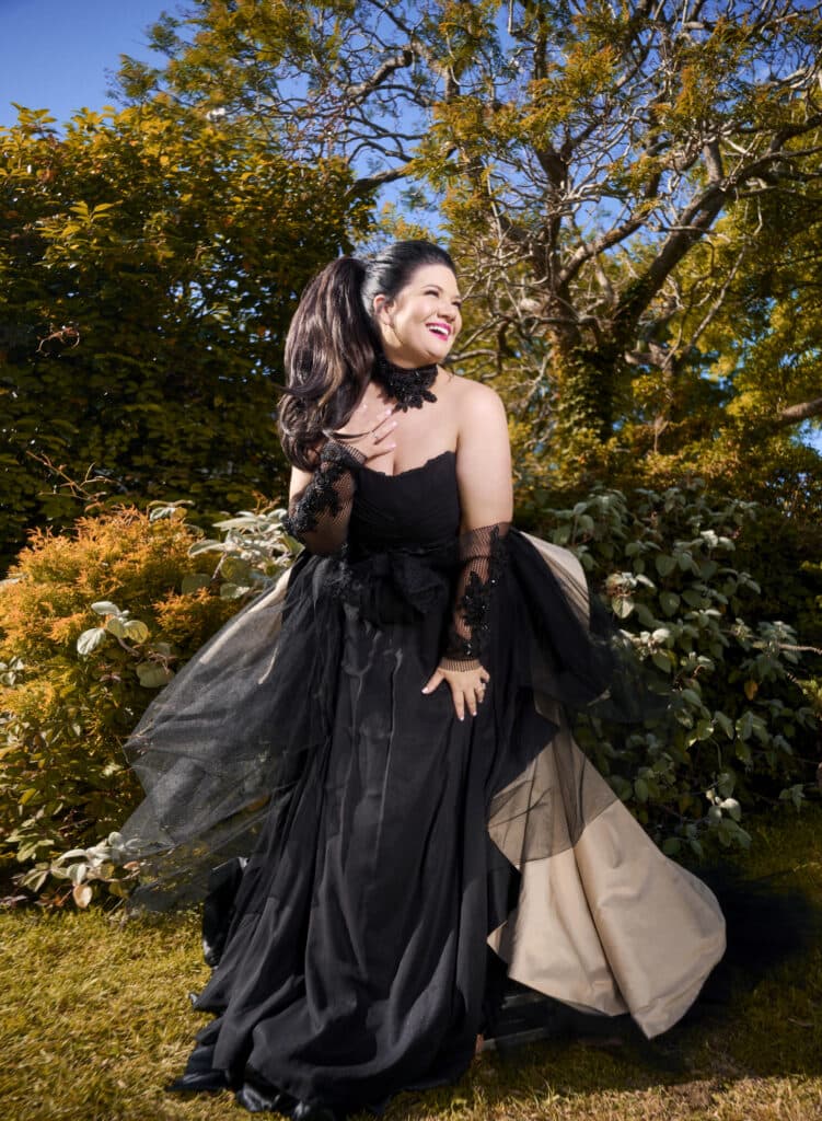 Tanya Hennessy in head-to-toe black evening wear amidst an autumn forest.