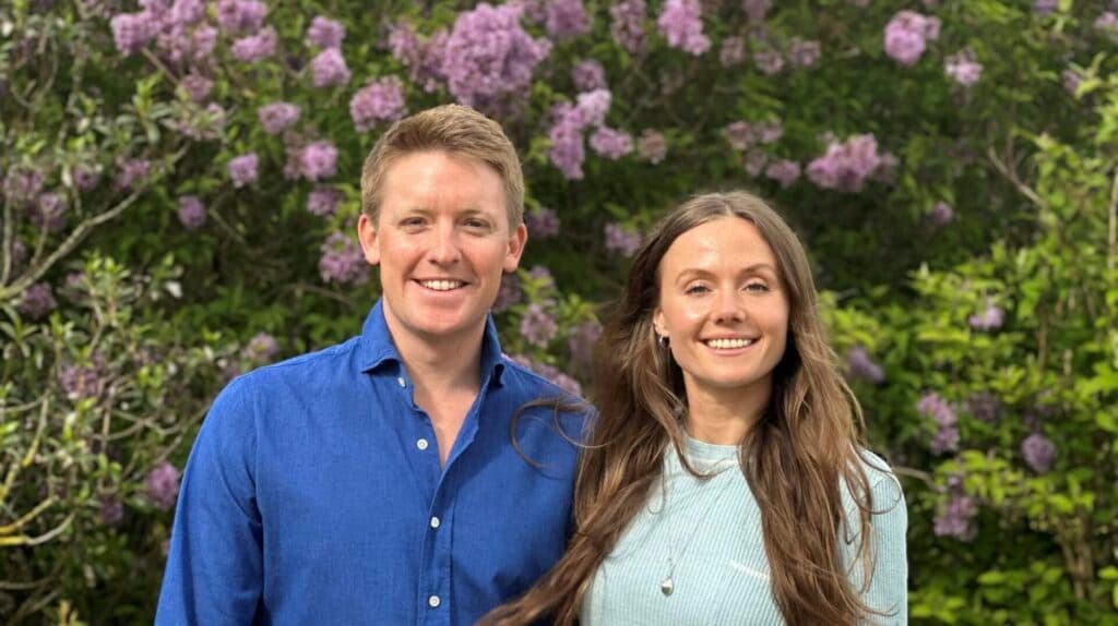 Hugh Grosvenor and Olivia Henson standing in front of a bush of purple flowers ahead of their royal wedding