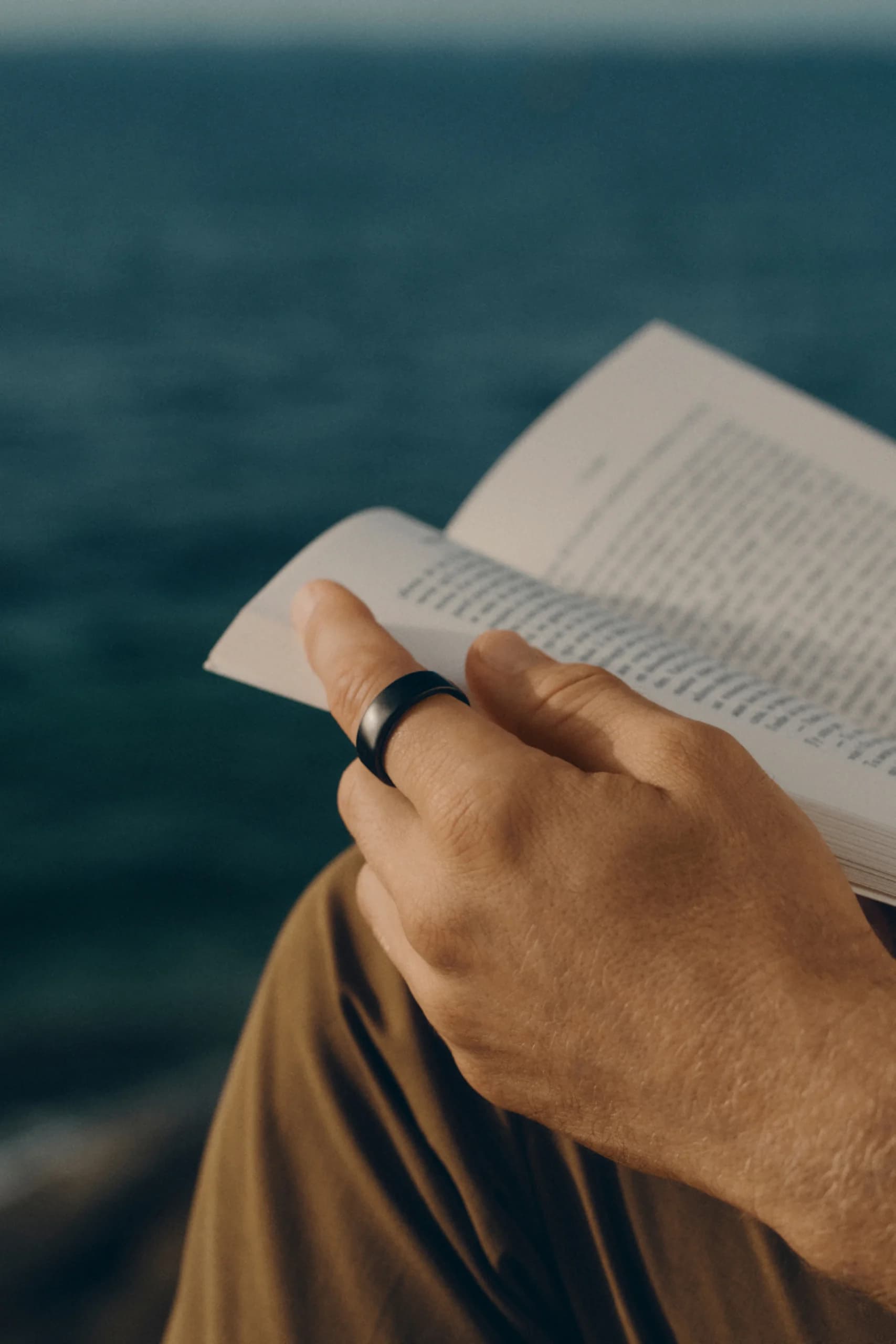 Close up of someone holding an open book, Oura Ring on finger