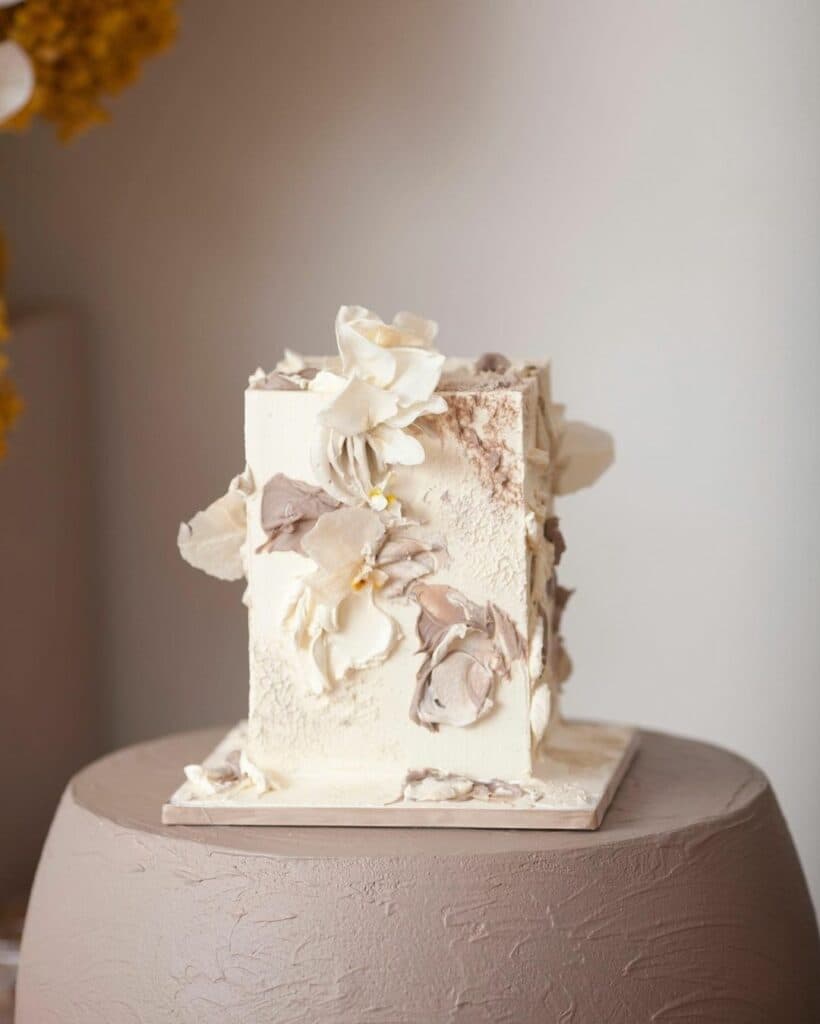 A non-traditionally shaped cake with different textures and florals.