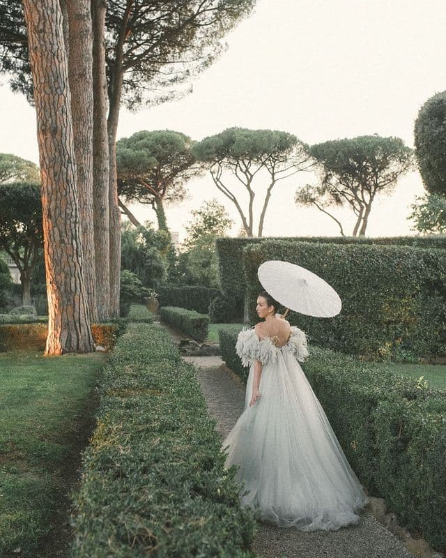 A beautiful bride walking in a garden in her sage green wedding dress.