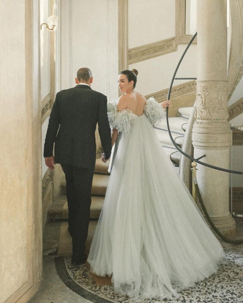 The loved up bride and groom making their way up an opulent staircase.