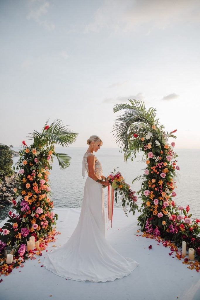 Tropical themed destination wedding with an arc with vibrant florals and greenery