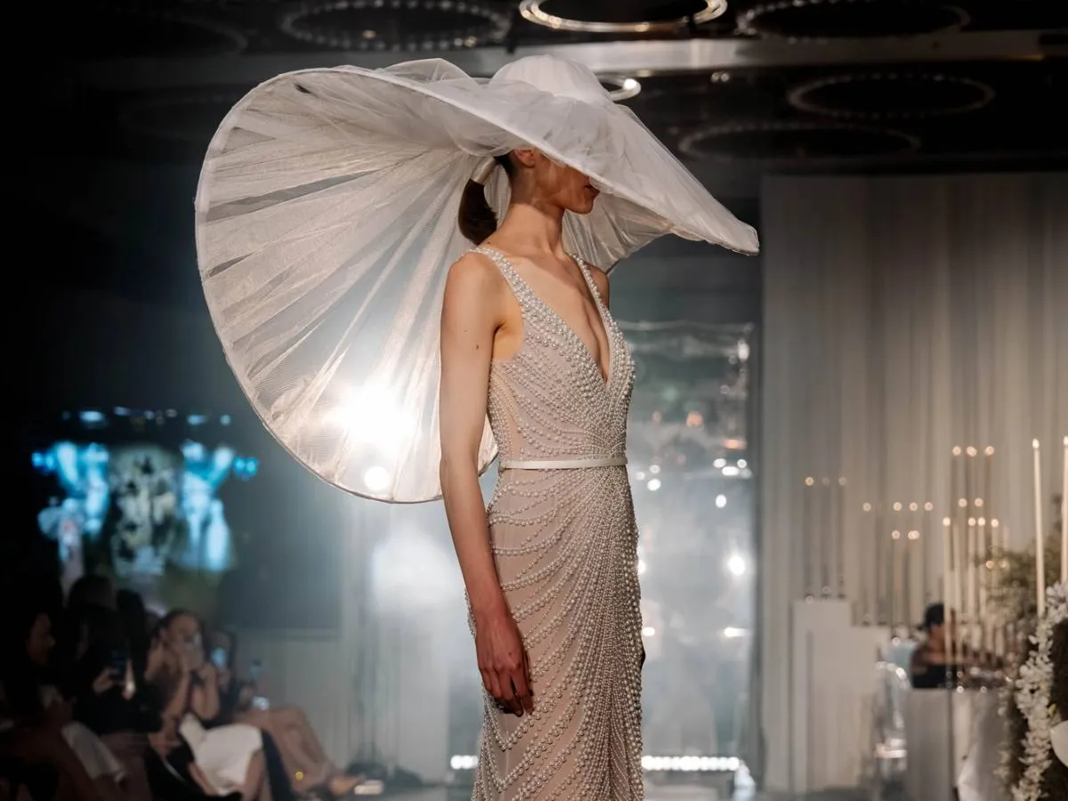A model in a sculptural bridal hat on the Wedded World runway