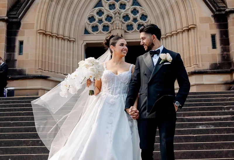 A bride and groom on the steps of a sandstone cathedral