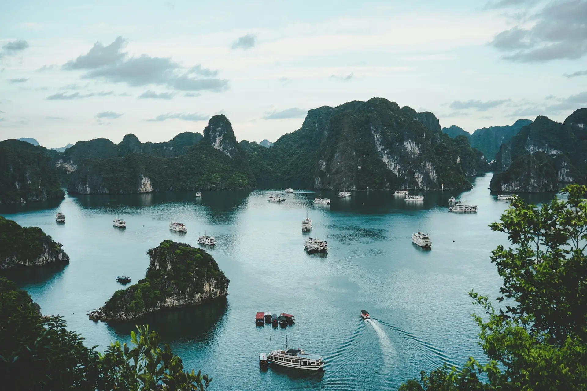 Travel packages, high-angle photography of boats on water near hill during daytime
