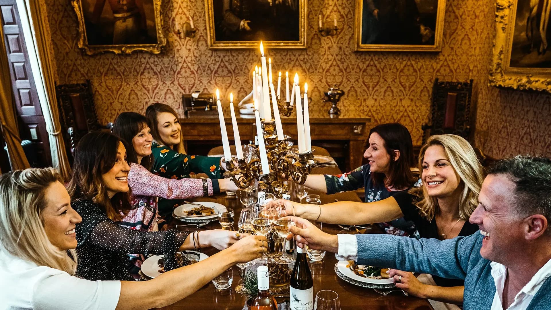 Wedding and honeymoon packages, group of people sitting on chair in front of table with plates and drinking glasses
