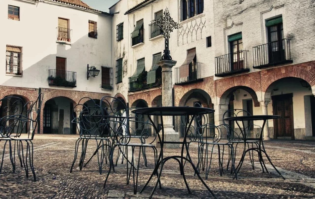 Iron cafe tables on a small arcaded square in an old Spanish town