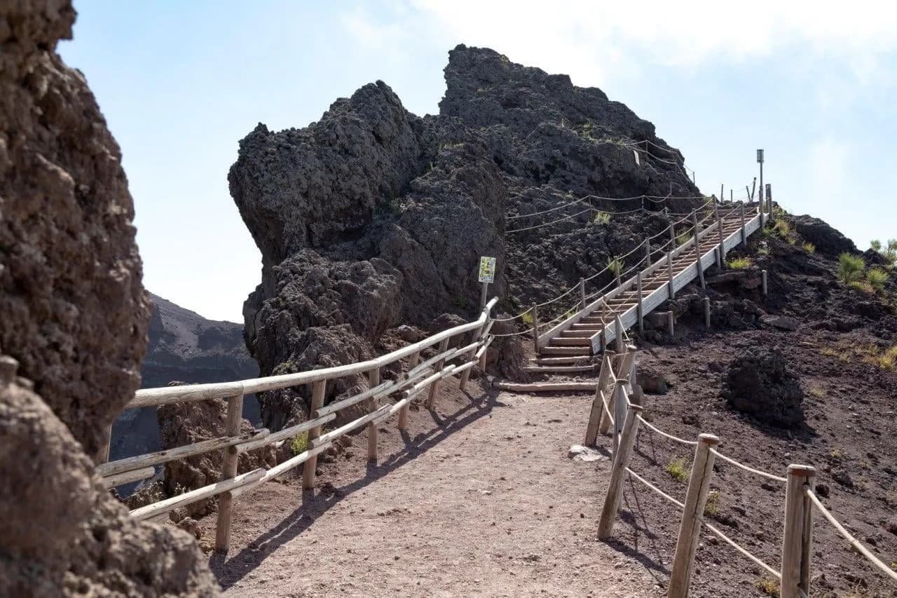 A fenced path and steps climbing past dark volcanic rock on Mount Vesuvius