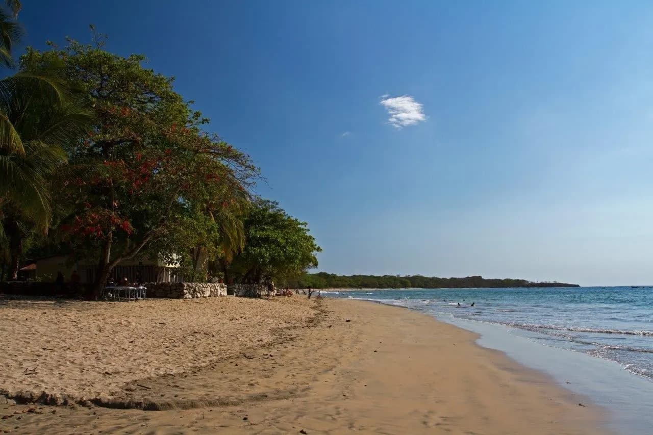 A wide sandy beach on the Pacific coast under a clear blue sky