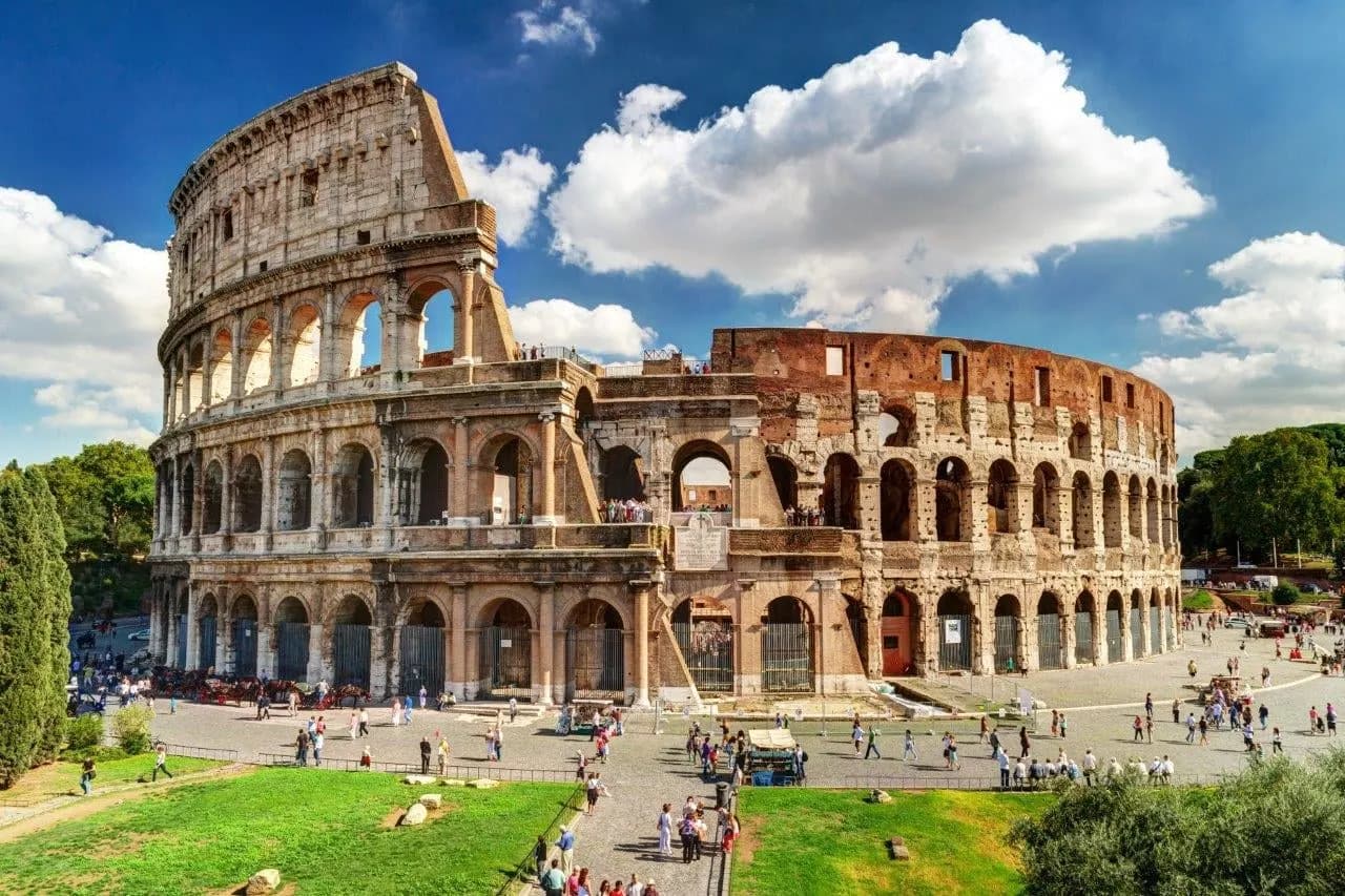 The Colosseum in Rome under a blue sky with white clouds