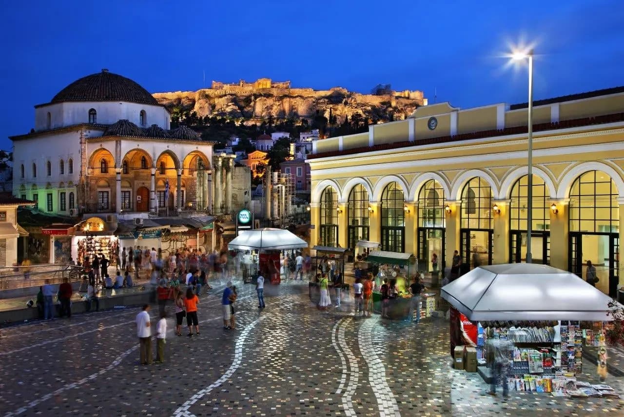 Monastiraki Square lit up at dusk, with the Acropolis above