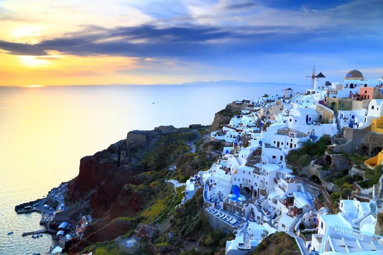 The white houses of Oia spilling down the cliff at sunset