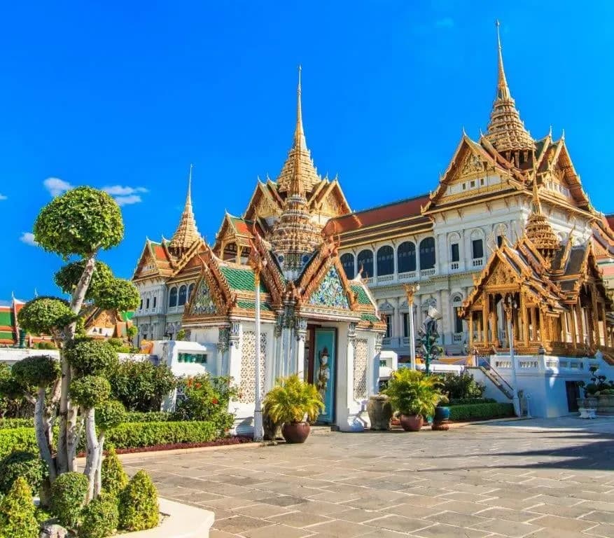 A white and gold throne hall with tiered roofs at the Grand Palace