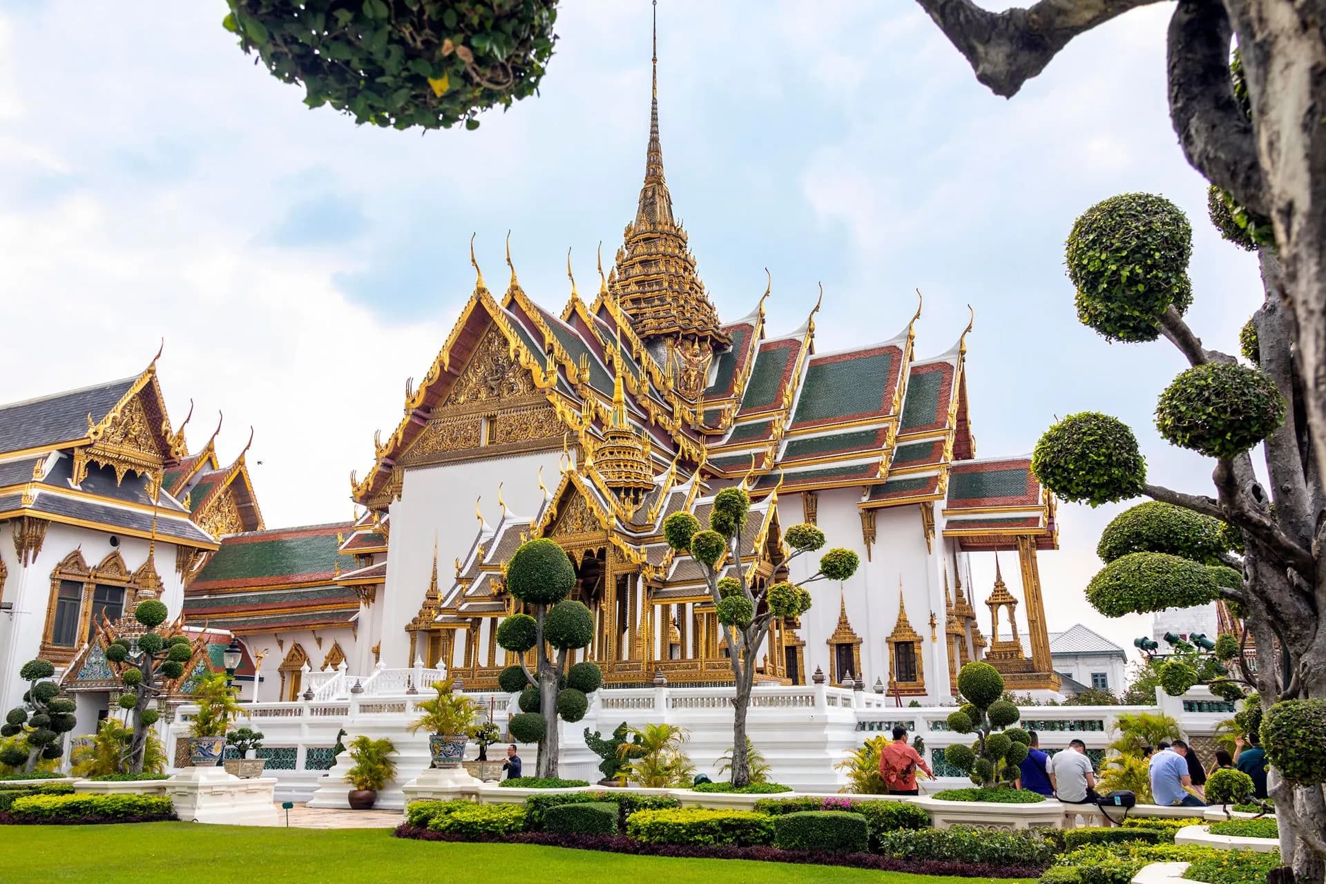 Gilded halls and trimmed trees in a courtyard of the Grand Palace, Bangkok