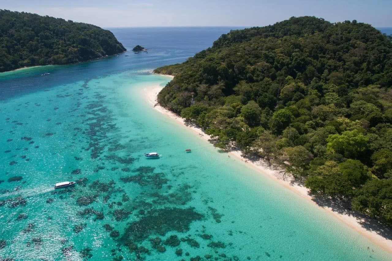 An island beach and turquoise shallows in the Andaman Sea from the air