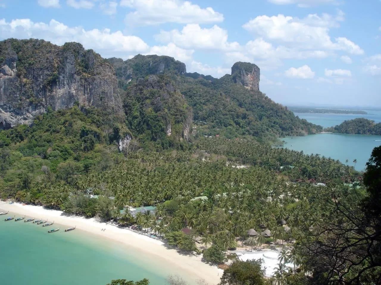 A white sand bay and limestone cliffs seen from a forested viewpoint near Krabi