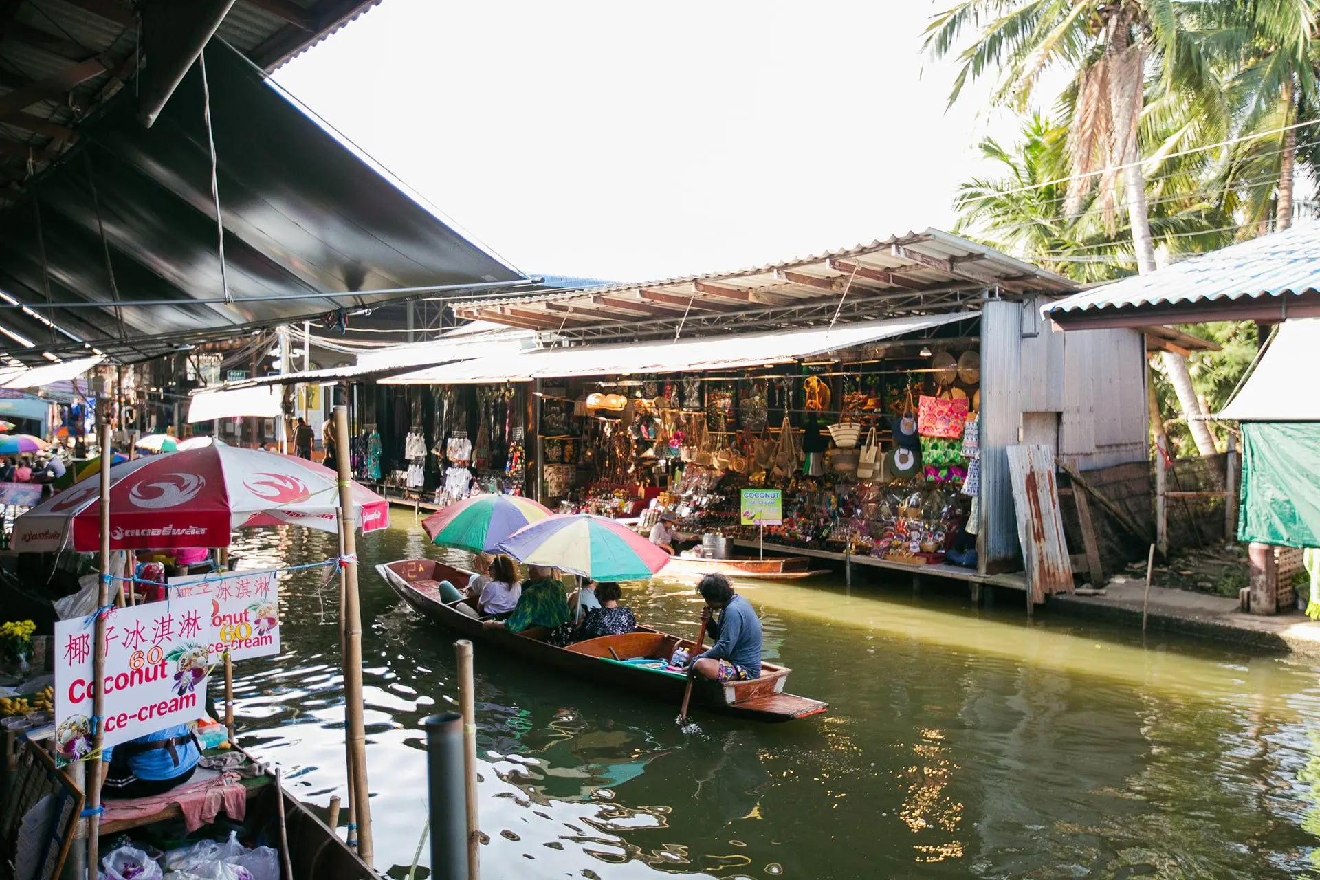 Market stalls and a paddled boat on a canal at Damnoen Saduak