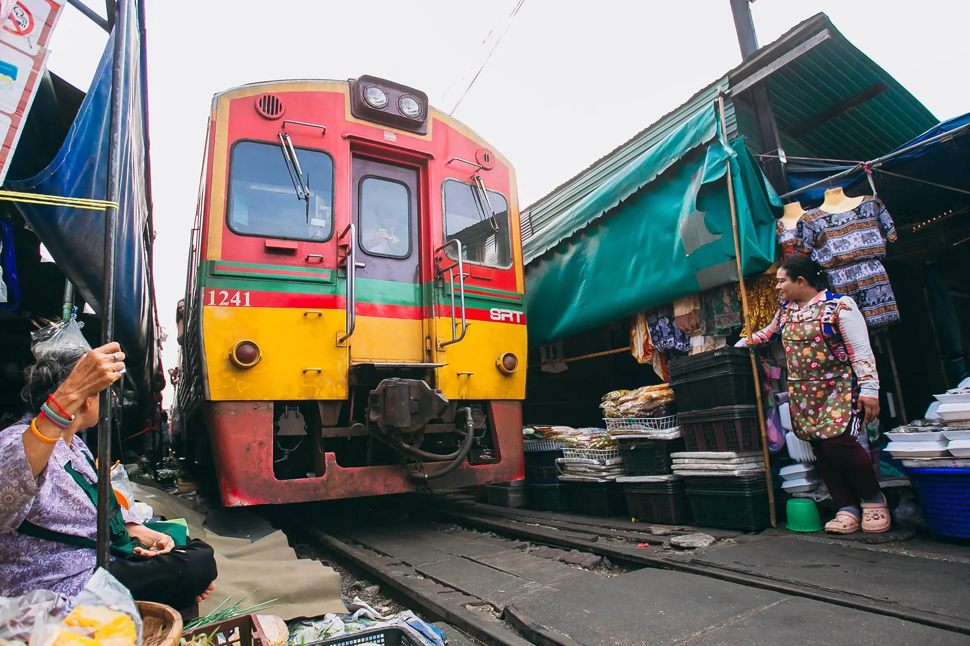 A train edging between stalls at the Maeklong railway market