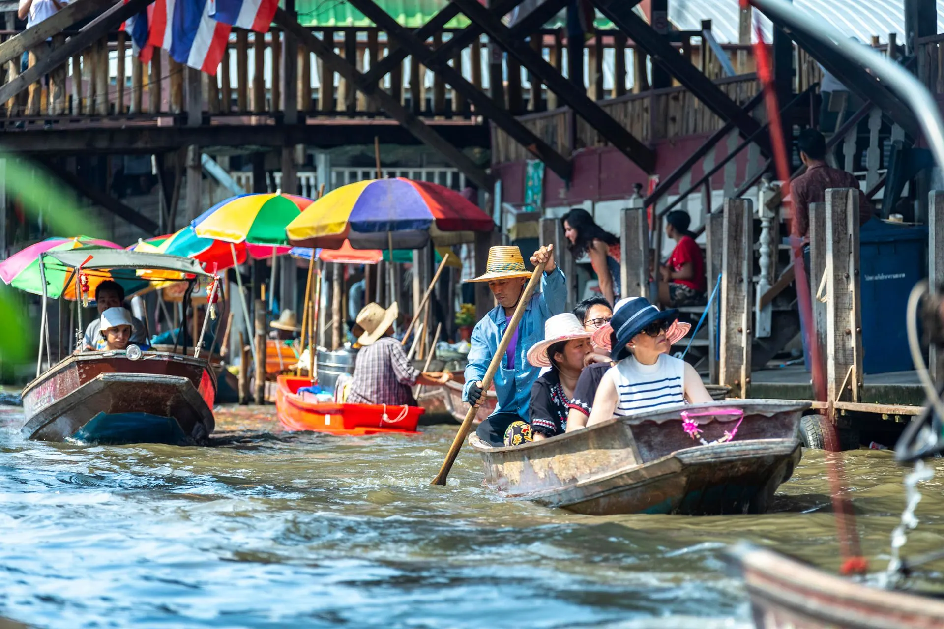 Paddle boats with sun umbrellas on the canal at Damnoen Saduak
