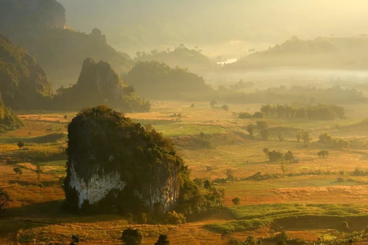 Morning mist over a valley of limestone outcrops and fields