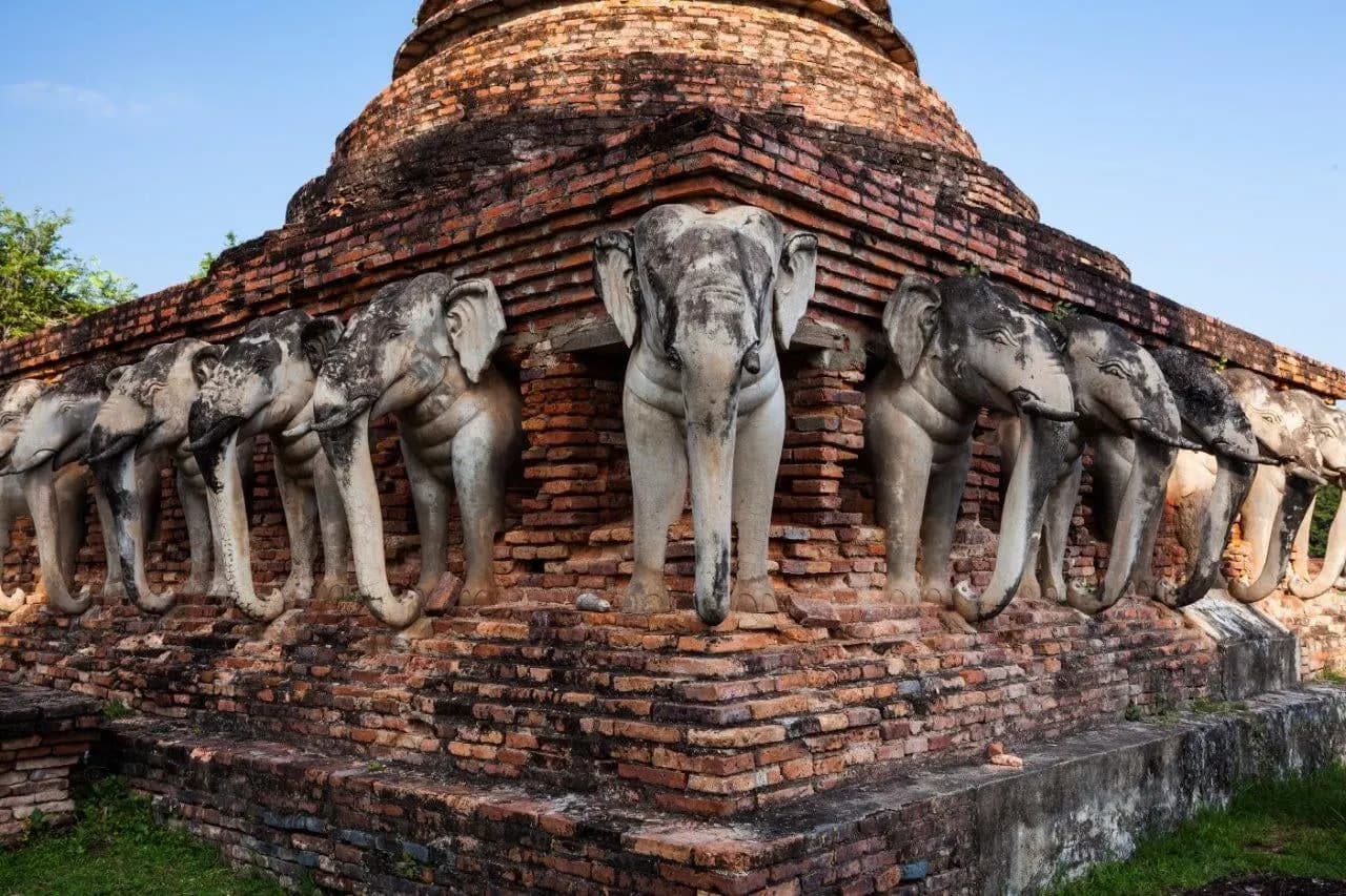 Stone elephants around the base of an old brick chedi