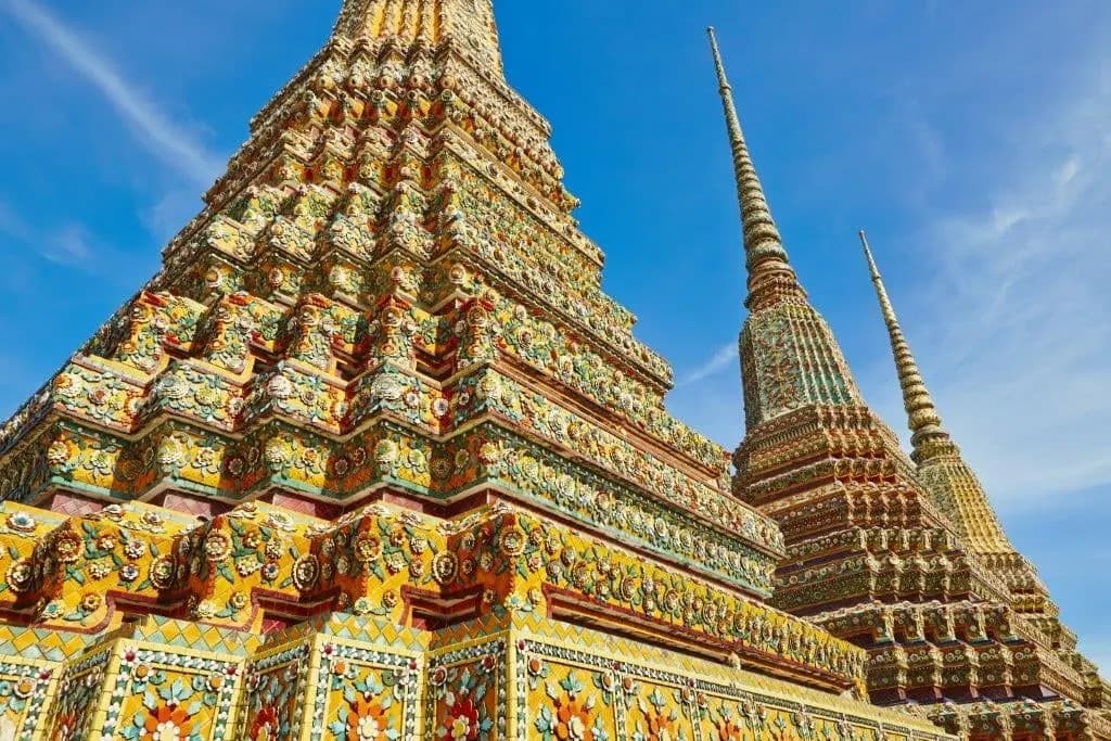 Mosaic-covered chedis at Wat Pho against a blue sky