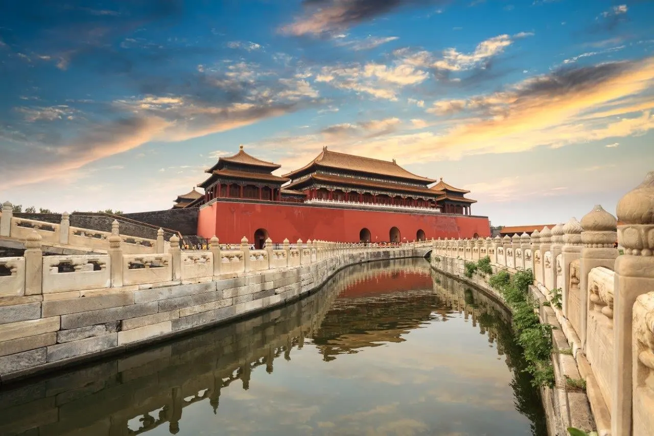 A corner of the Forbidden City reflected in its moat under an evening sky