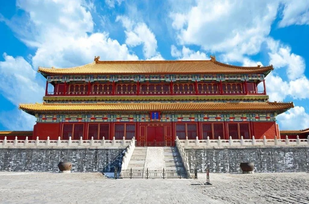 A red and gold imperial hall on its white stone terrace under a blue sky