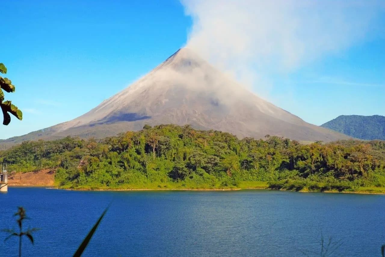 Arenal Volcano with a plume of cloud above a blue lake