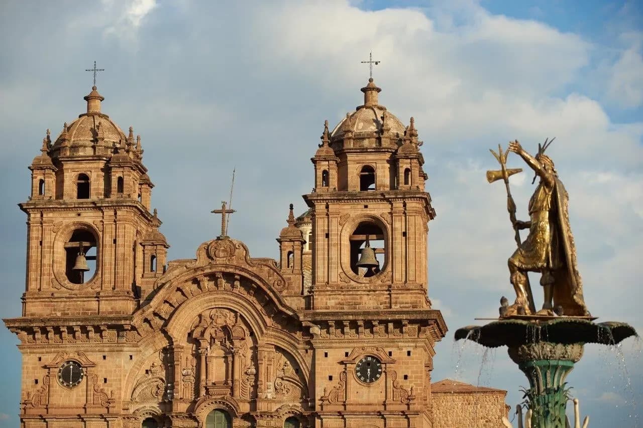 Twin bell towers of a church on the main square in Cusco beside a fountain