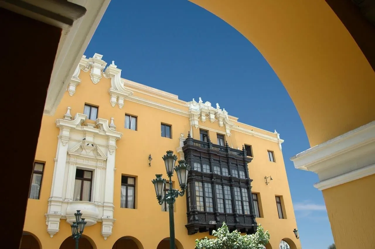 A yellow colonial building with a dark carved wooden balcony in central Lima