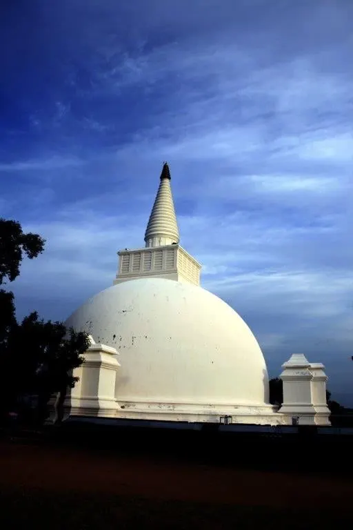 A white dagoba with a gilded spire under a deep blue sky