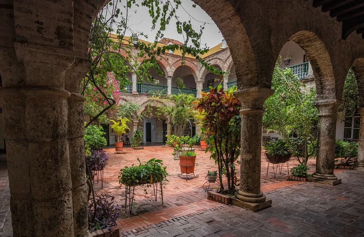 Stone arches and potted plants around a colonial cloister courtyard