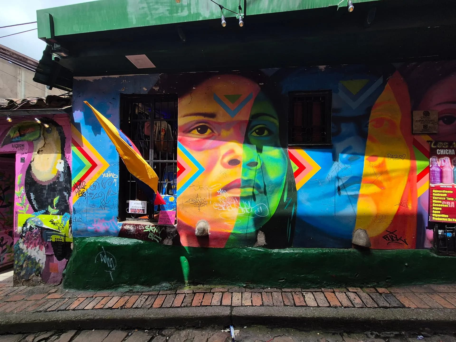 A bright mural of faces painted across a building in Bogotá