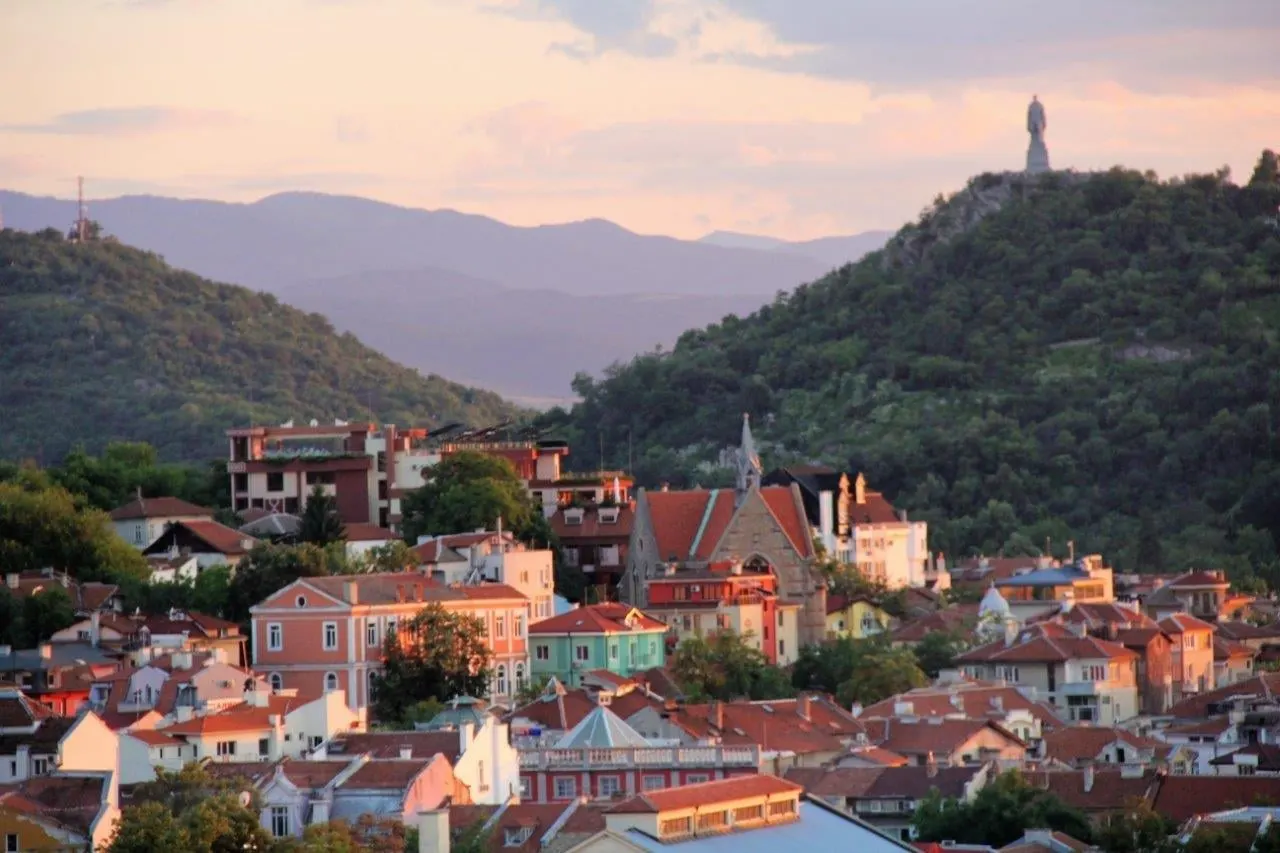 Colourful houses of Plovdiv below wooded hills at dusk