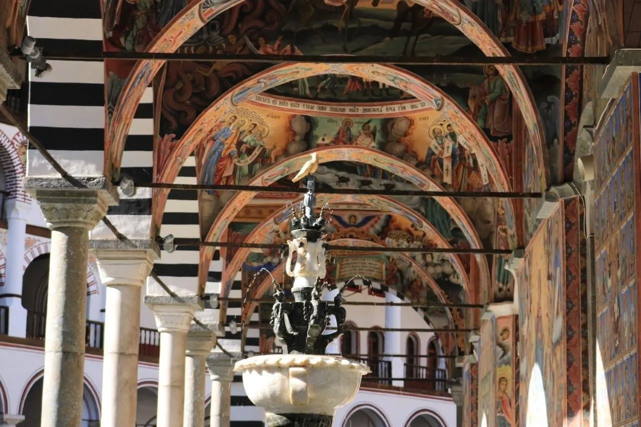 Painted arches and a stone fountain in the courtyard of a monastery