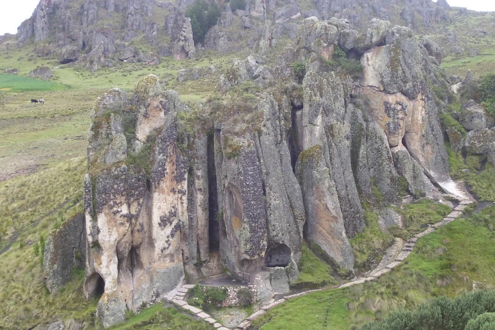 Tall grey rock formations of the Cumbemayo stone forest above green fields