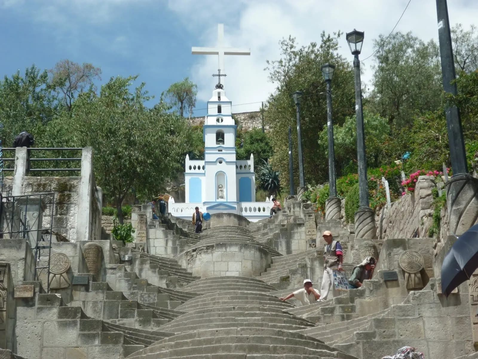 A wide stone stairway climbing to a white chapel and cross on Santa Apolonia hill