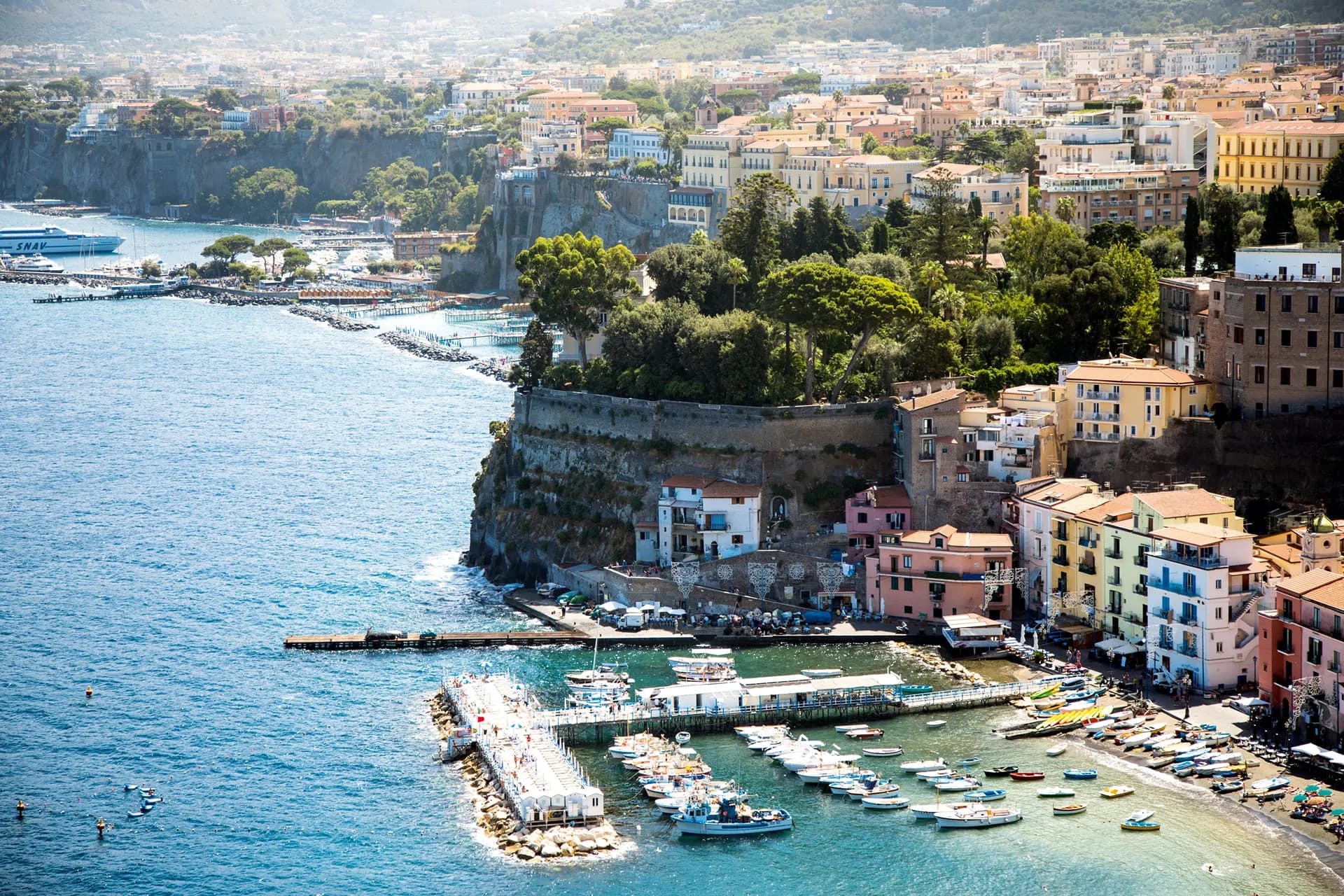 The harbour of Sorrento with boats below a cliff of pastel buildings