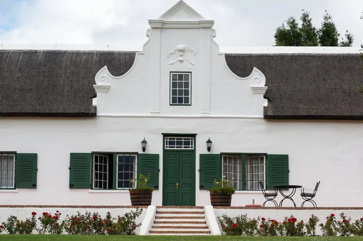 The white curved gable and green shutters of a Cape Dutch manor house