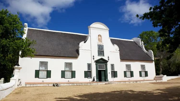 A thatched Cape Dutch homestead with a white gable under a blue sky