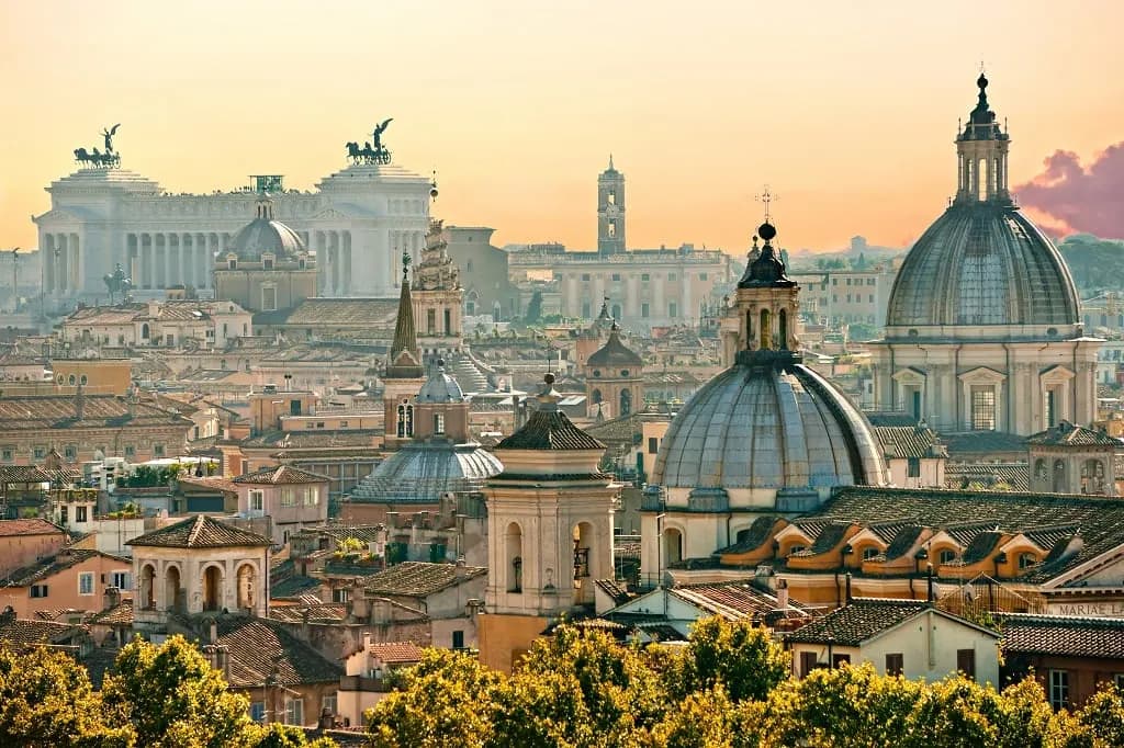 Church domes and the Vittoriano rising over the rooftops of Rome at sunset