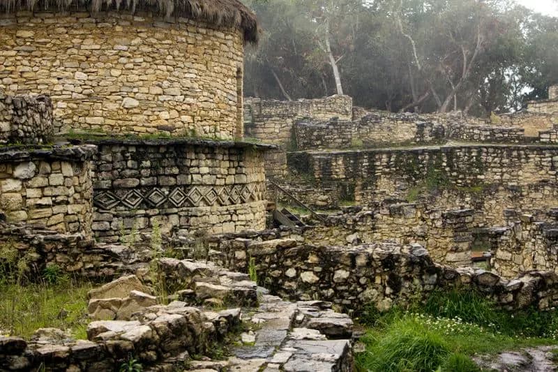 Stone walls and terraces of Kuélap with trees in the mist behind