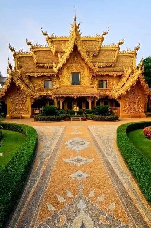 An ornate golden temple hall at the end of a patterned path