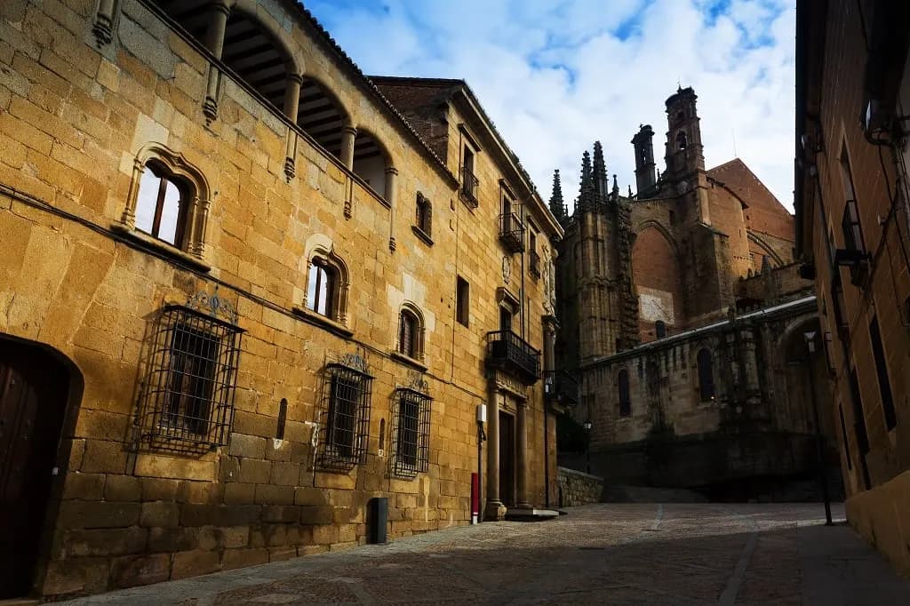 A quiet street of golden stone palaces leading to a Gothic church