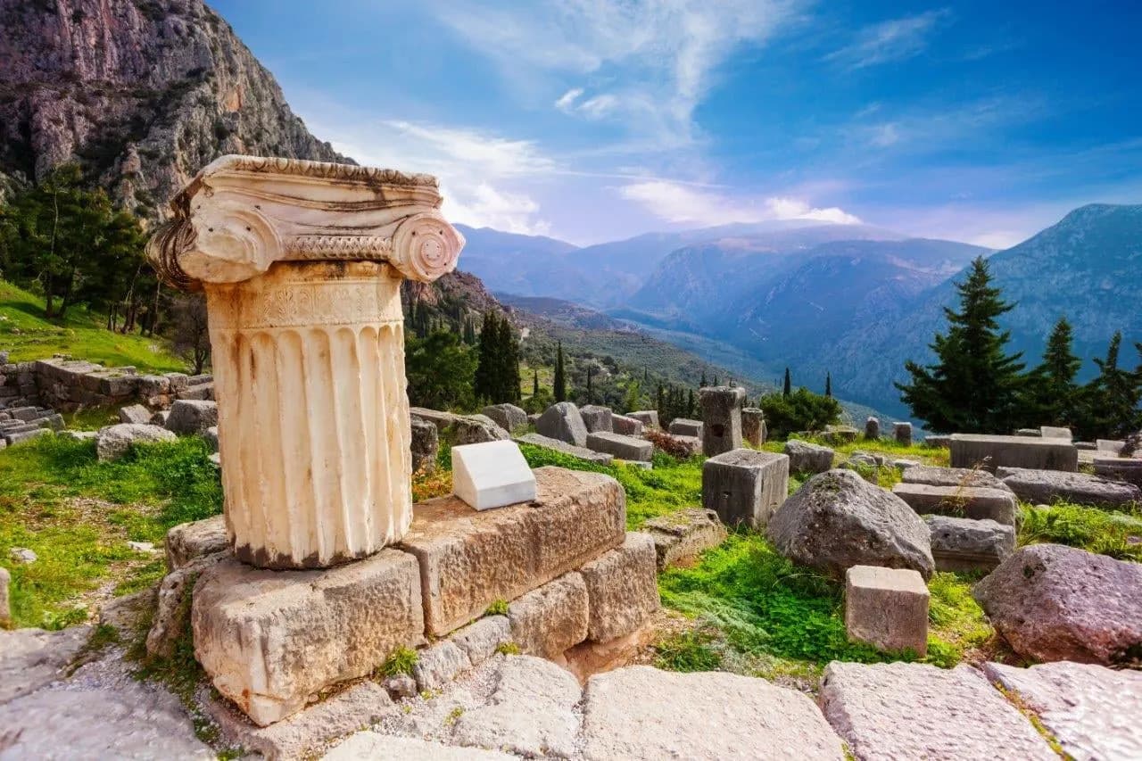 A fallen Ionic column among the ruins of Delphi, with the valley below