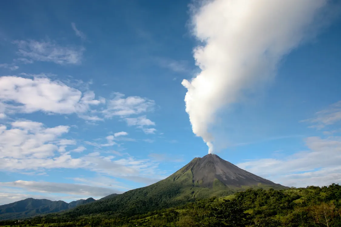 Arenal Volcano with a white plume of cloud rising from its peak