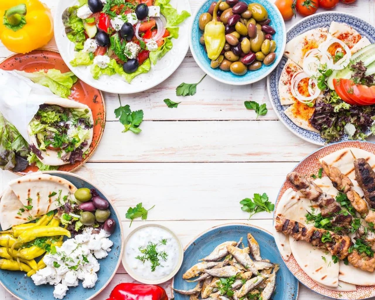 A table of Greek dishes with olives, salads, souvlaki and tzatziki
