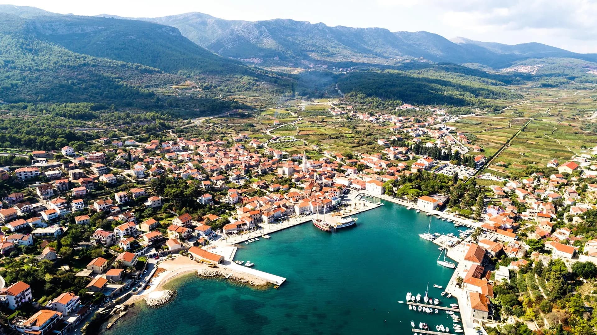 A harbour town on a Dalmatian island with vineyards and hills behind
